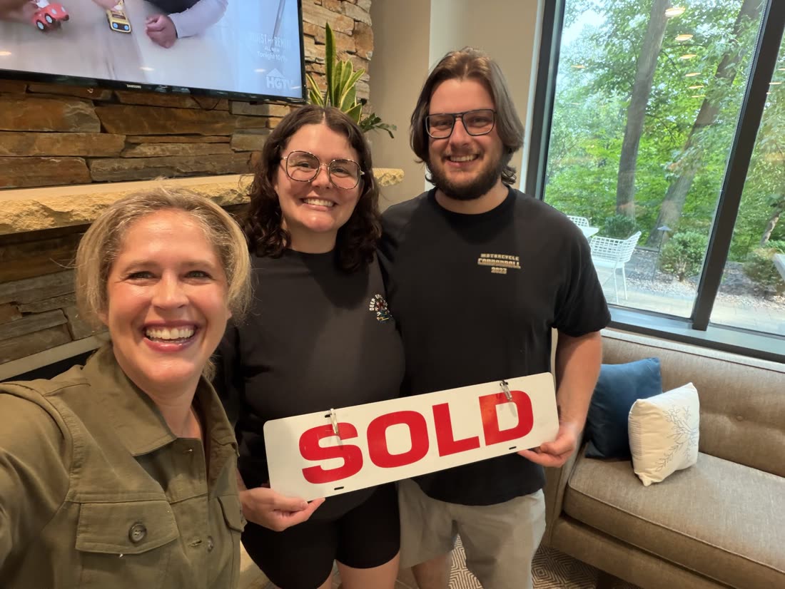 Andrea Scanlon taking a selfie with two clients holding a SOLD sign