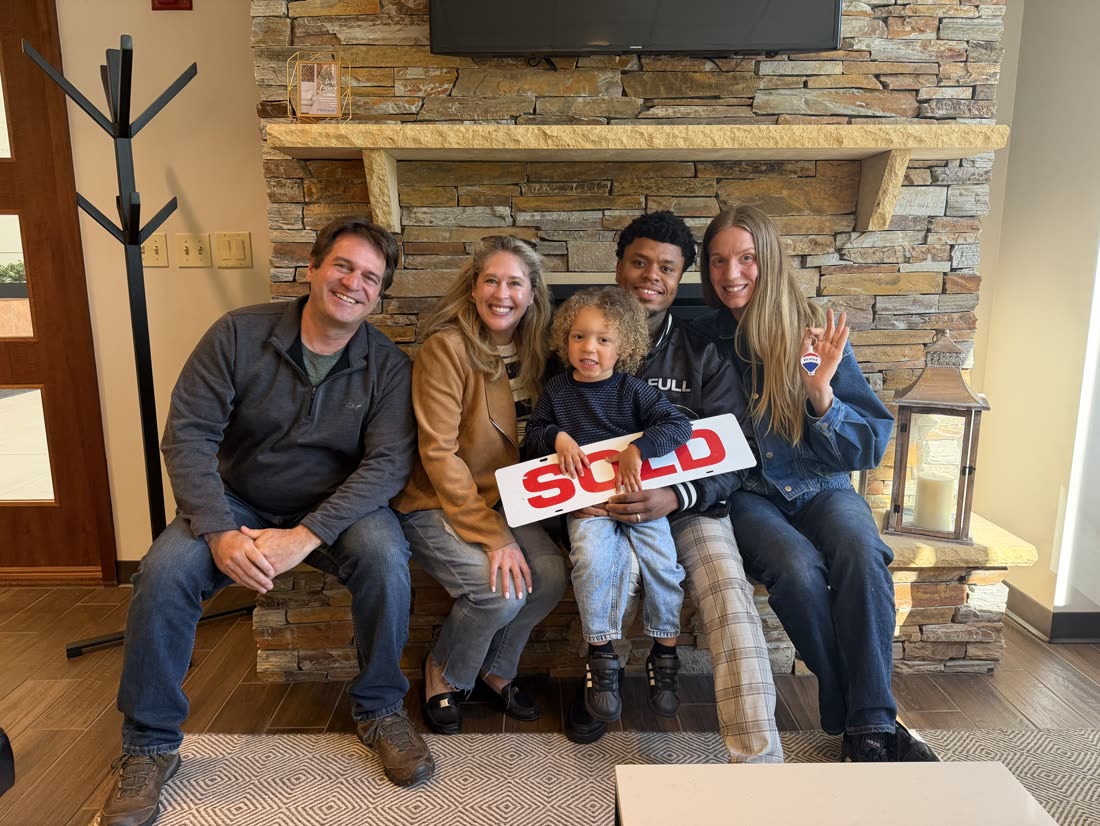 A family with their children holding a SOLD sign on closing day